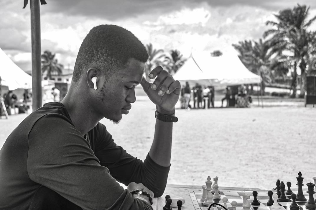 A black-and-white portrait of a guest beside a giant chess set